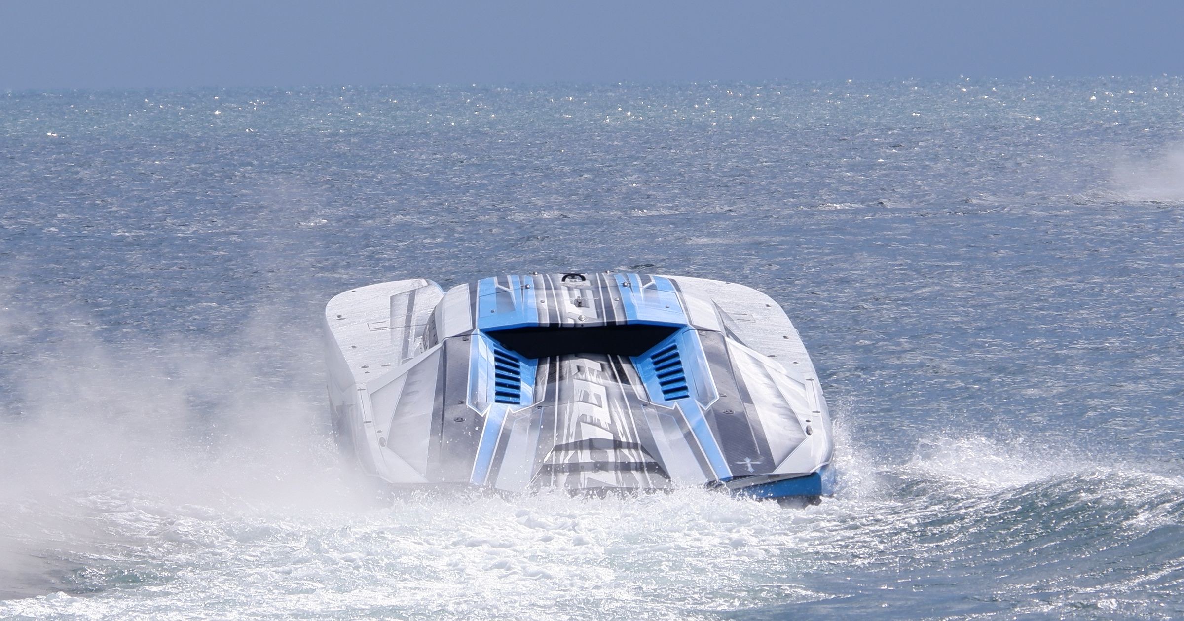 Offshore performance catamaran running head-on through spray